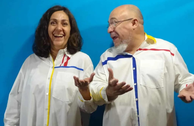 Mujer a la izquierda y hombre mirándola a la la derecha. Ambos visten una bata blanca con adornos de colores