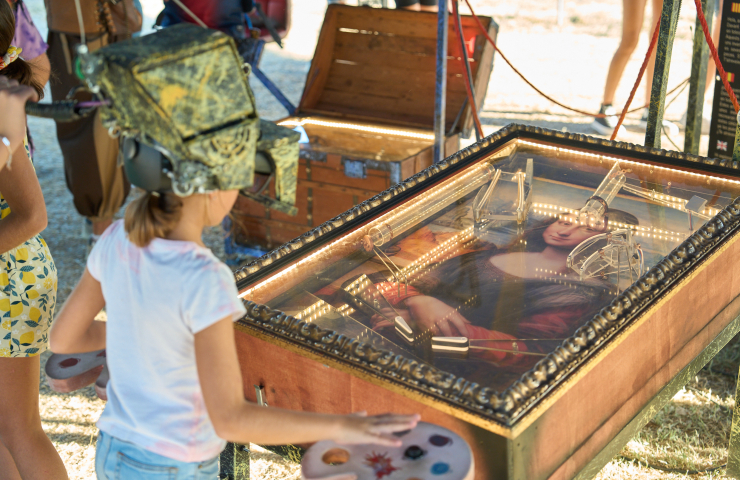 Niña jugando al pinball, con la imagen de La Gioconda como parte del panel del juego